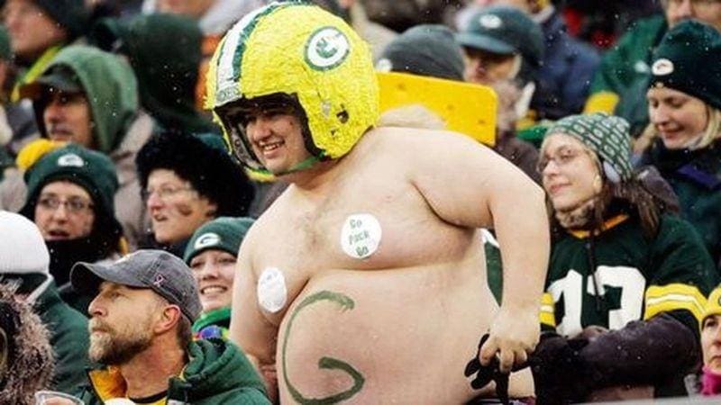 A man in green bay packers gear is standing up.