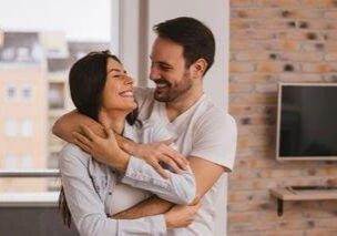 A man and woman hugging in front of a brick wall.