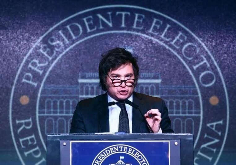 A man in glasses and suit giving a speech.