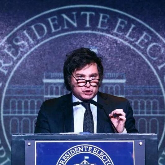 A man in glasses and suit giving a speech.